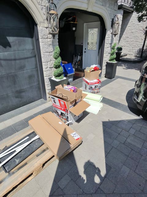 Boxes, a pallet and old items gathered on a driveway for pickup