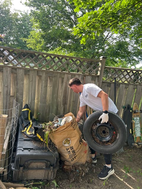 Benny carrying an old tire out of a backyard full of junk