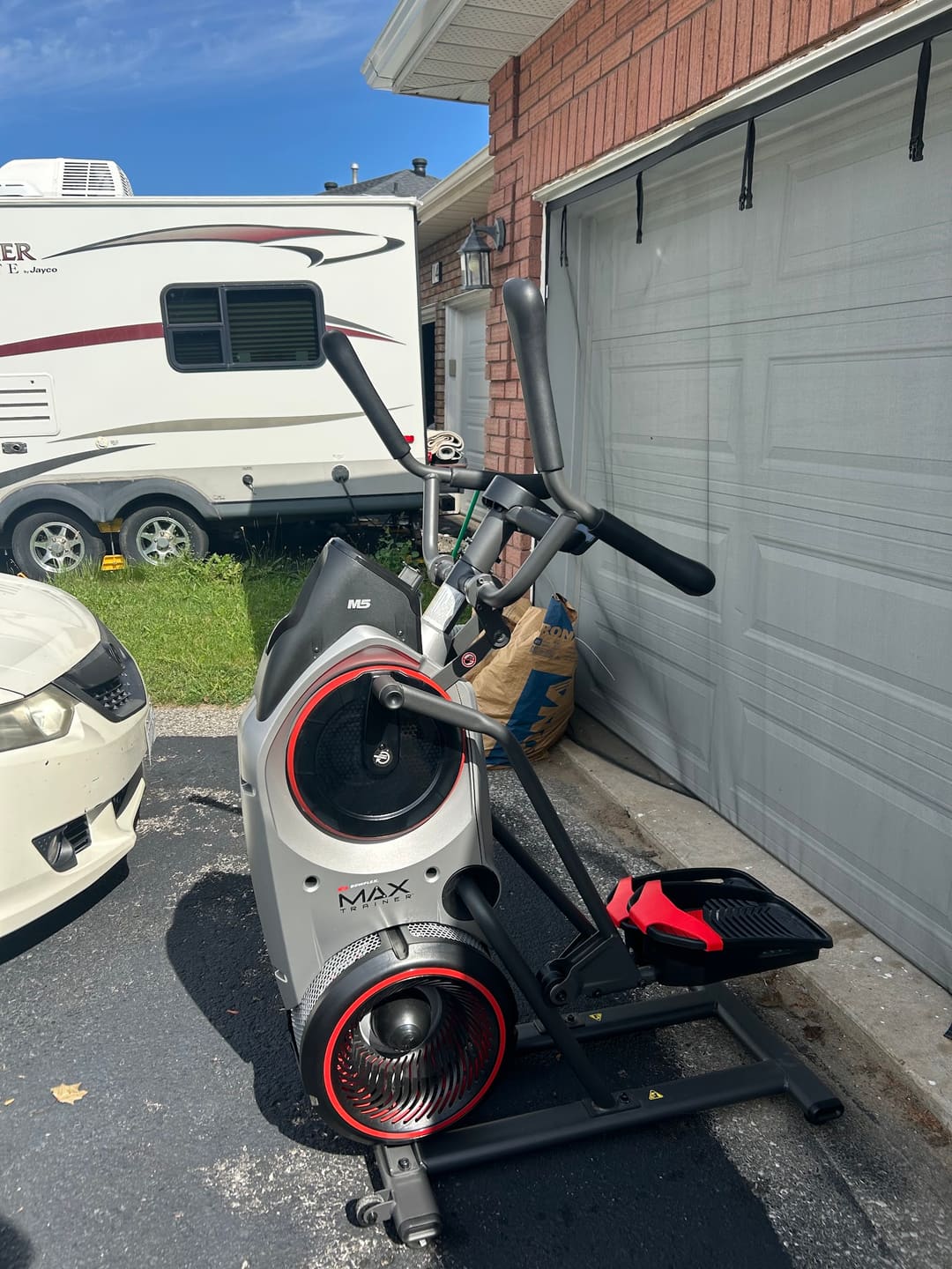 An exercise bike waiting for pickup in a driveway
