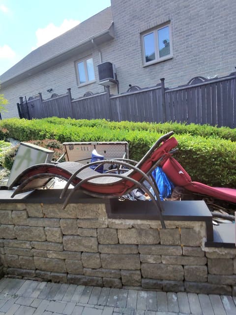 Old red patio furniture piled behind a stone wall