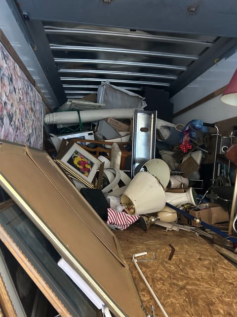A truck packed to the roof with furniture, lamps and boards