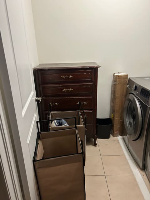 A wooden dresser and bins in a laundry room, ready to go