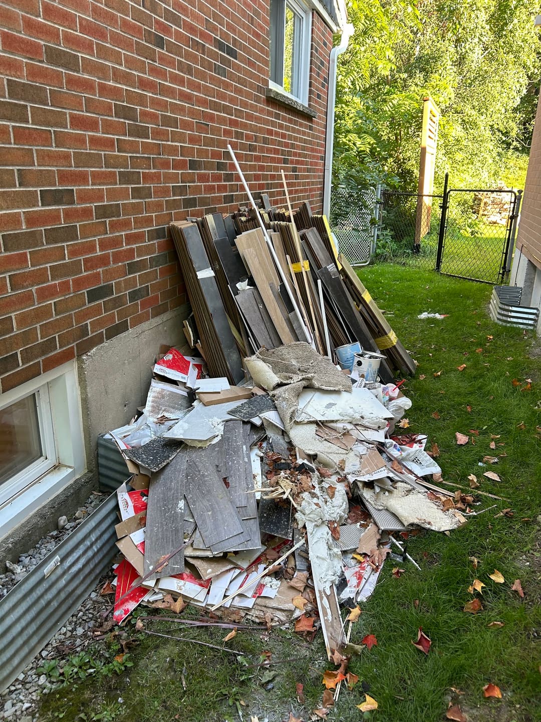Renovation debris and boards piled beside a brick house