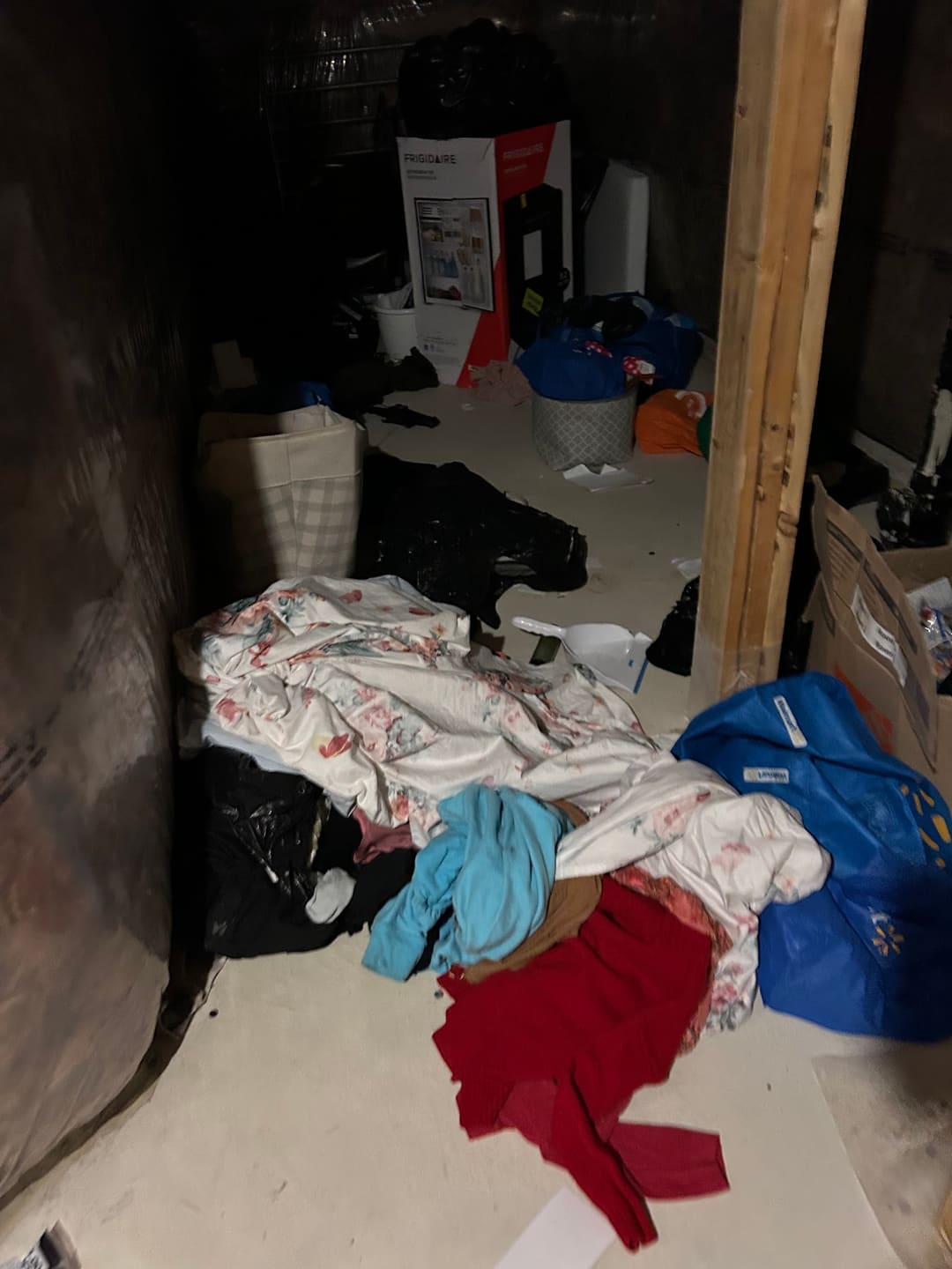 A storage room with clothes, bags and boxes on the floor before a cleanout