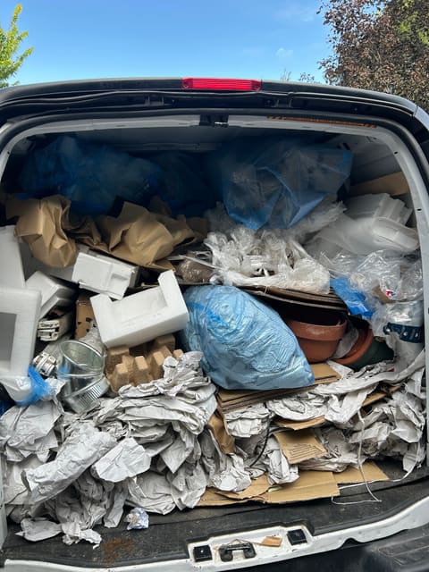 Bags, boxes and packing material loaded in the back of a vehicle